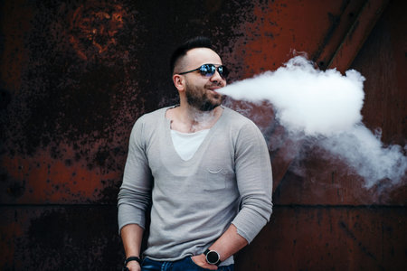 Men with beard vaping outdoor in sunglasses