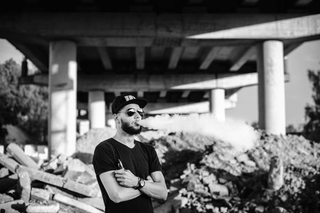 Men with beard vaping outdoor in sunglasses