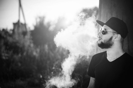 Men with beard vaping outdoor in sunglassesの写真素材