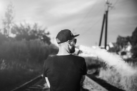 Men with beard vaping outdoor in sunglasses