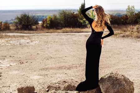Woman in long black dress walking outdoorの写真素材