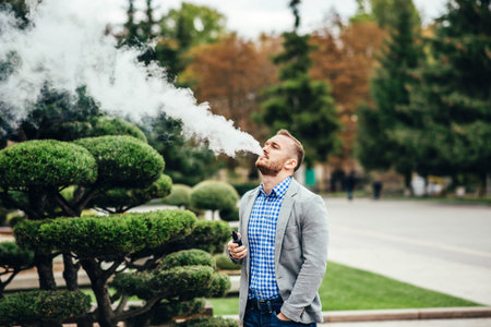 Men with beard vaping electronic cigarette outdoor