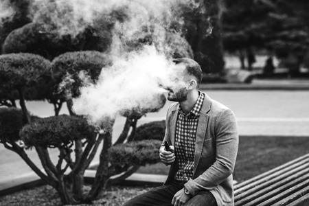 Men with beard smoking electronic cigarette outdoorの写真素材