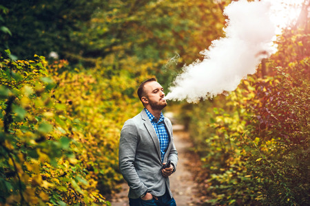 Men with beard smoking electronic cigarette outdoorの写真素材