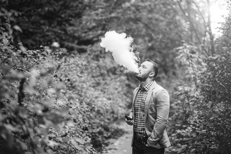 Men with beard smoking electronic cigarette outdoorの写真素材