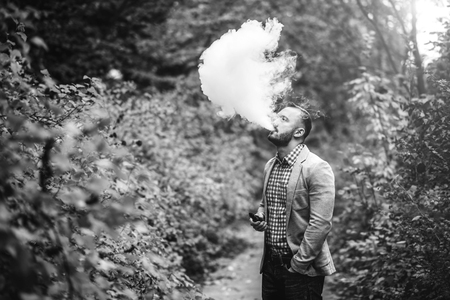 Men with beard smoking electronic cigarette outdoorの写真素材