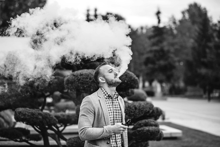 Men with beard vaping electronic cigarette outdoorの写真素材