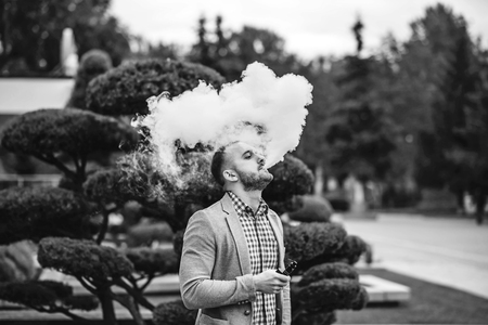 Men with beard vaping electronic cigarette outdoorの写真素材