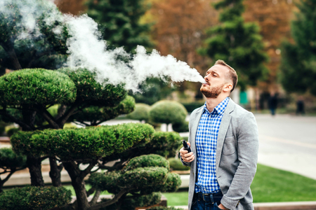 Men with beard vaping electronic cigarette outdoorの写真素材