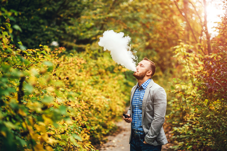 Men with beard smoking electronic cigarette outdoorの写真素材