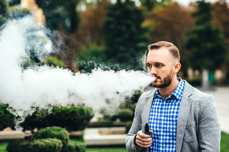 Men with beard smoking electronic cigarette outdoorの写真素材
