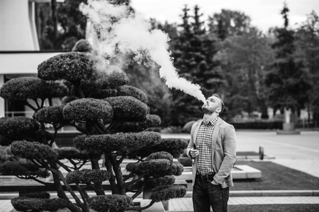 Men with beard vaping electronic cigarette outdoorの写真素材
