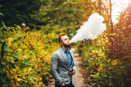 Men with beard smoking electronic cigarette outdoorの写真素材