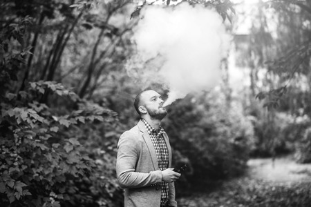 Men with beard smoking electronic cigarette outdoorの写真素材