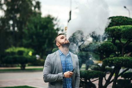 Men with beard vaping electronic cigarette outdoorの写真素材
