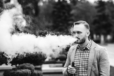 Men with beard smoking electronic cigarette outdoorの写真素材