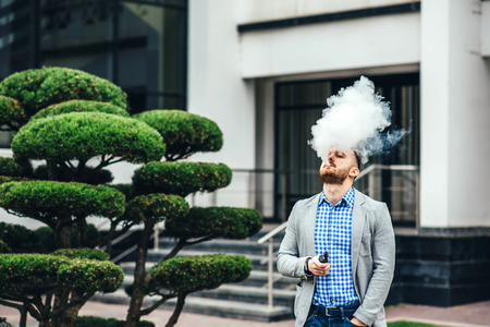 Men with beard vaping electronic cigarette outdoorの写真素材