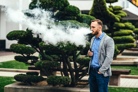 Men with beard vaping electronic cigarette outdoorの写真素材