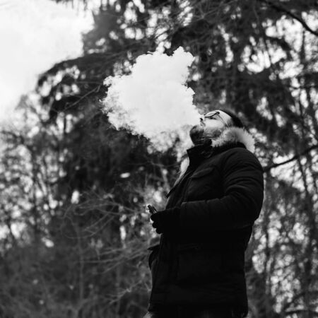 Man with beard smoke electronic cigarette outdoorの写真素材