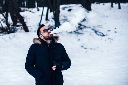Man vith beard smoke electronic cigarette outdoorの写真素材