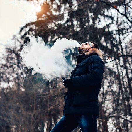 Man with beard smoke electronic cigarette outdoorの写真素材