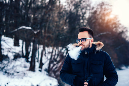 Man with beard smoke electronic cigarette outdoorの写真素材
