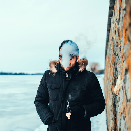 Man with beard smoke electronic cigarette outdoorの写真素材