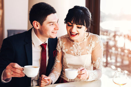 Happy wedding couple relaxing in cafe togetherの写真素材