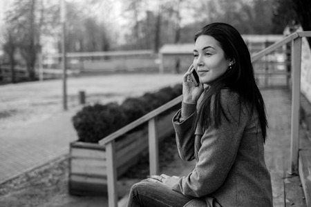 Young brunette girl in the park with mobile phoneの写真素材