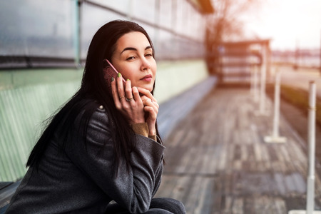 Young brunette girl in the park with mobile phoneの写真素材