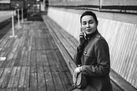 Young brunette girl sitting outdoor with mobile phoneの写真素材