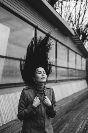 Young brunette woman outdoor with blowing up hair の写真素材
