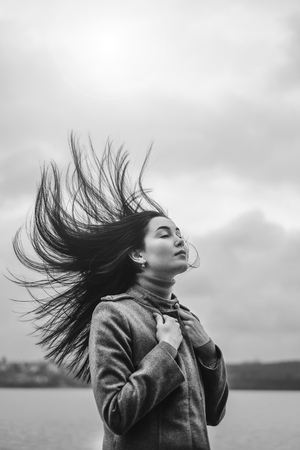 Young brunette woman outdoor with blowing up hairの写真素材