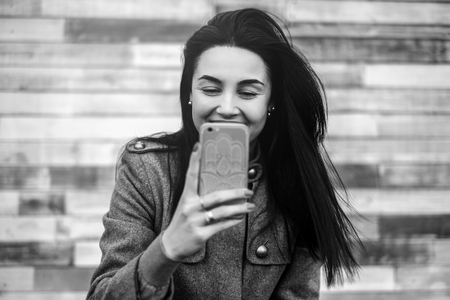 Young brunette girl in the park with mobile phoneの写真素材