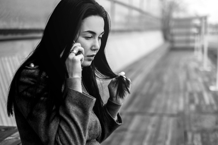 Young brunette girl in the park with phoneの写真素材