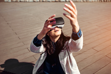 Brunette girl outdoor enjoying virtual reality glassesの写真素材