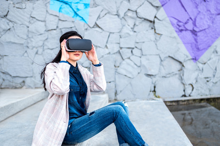Brunette girl outdoor enjoying virtual reality glassesの写真素材
