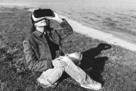 Young girl in virtual reality glasses outdoor, black and whiteの写真素材