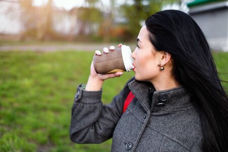 Long hair brunette girl with cup of coffee outdoorの写真素材