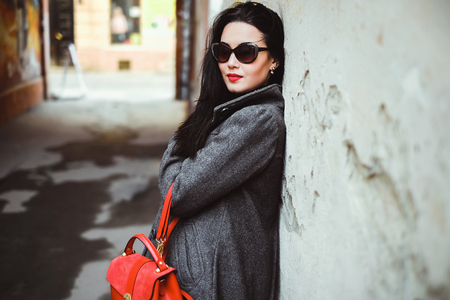 Long hair brunette girl near old wall with red backpackの写真素材