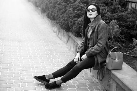 Young brunette girl sitting outdoor with red backpack, black and whiteの写真素材