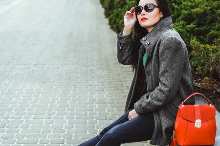 Young brunette girl sitting outdoor with red backpackの写真素材