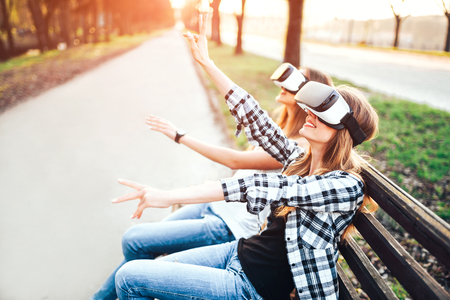 Two young girls enjoy virtual reality glasses outdoorの写真素材