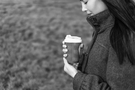 Long hair brunette girl with cup of coffee outdoor, black and whiteの写真素材