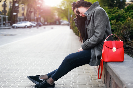 Young brunette girl sitting outdoor with red backpackの写真素材
