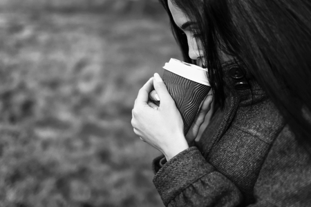 Long hair brunette girl with cup of coffee outdoor, black and whiteの写真素材