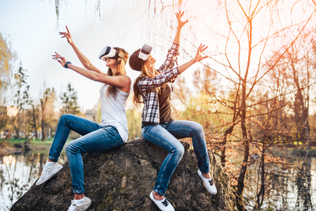 Two young girls enjoy virtual reality glasses outdoorの写真素材
