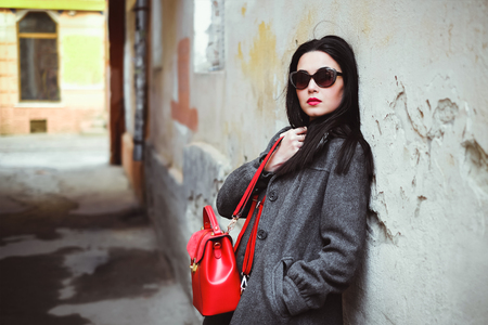 Long hair brunette girl near old wall with red backpackの写真素材