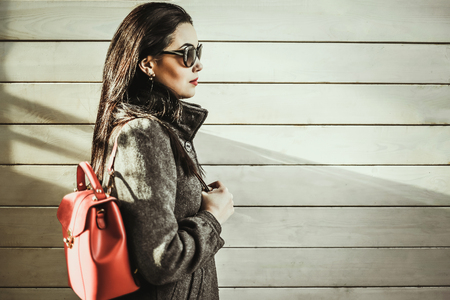 Long hair brunette girl near wooden wall with red backpackの写真素材