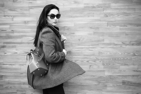 Long hair brunette girl near wooden wall with backpack, black and whiteの写真素材